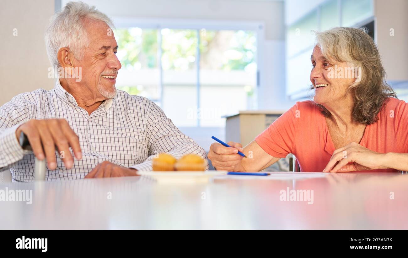 Happy senior retired couple solving puzzles at home as memory training Stock Photo