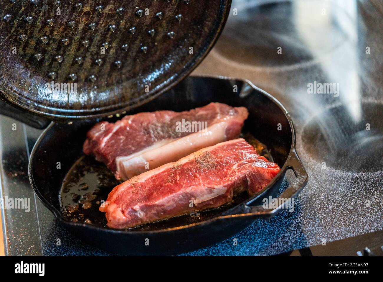 Premium Photo  Frying new york strip steak in cast iron frying pan over  the electric stove