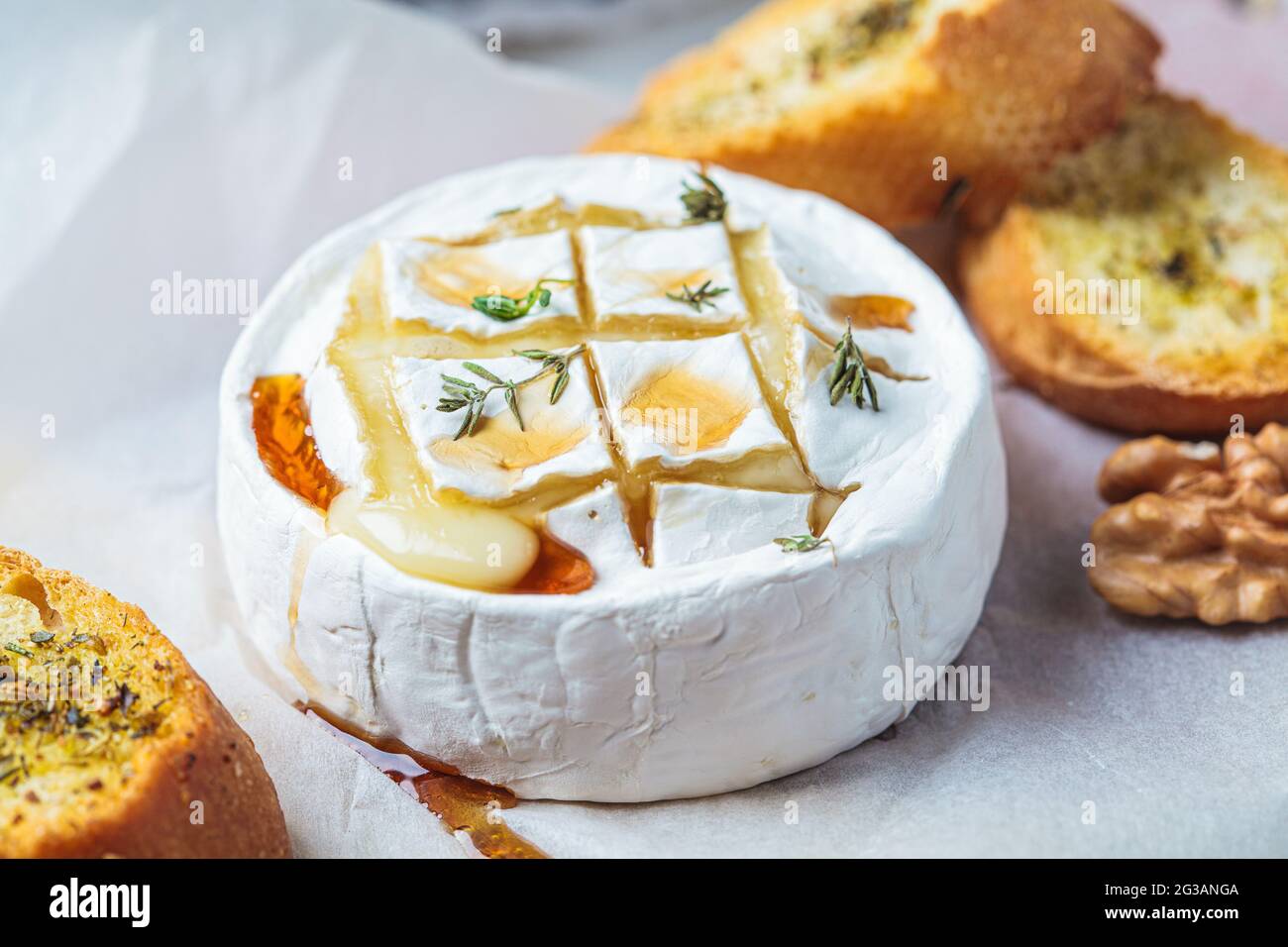 Baked Camembert or Brie with thyme,  maple syrup, nuts and bread. Stock Photo