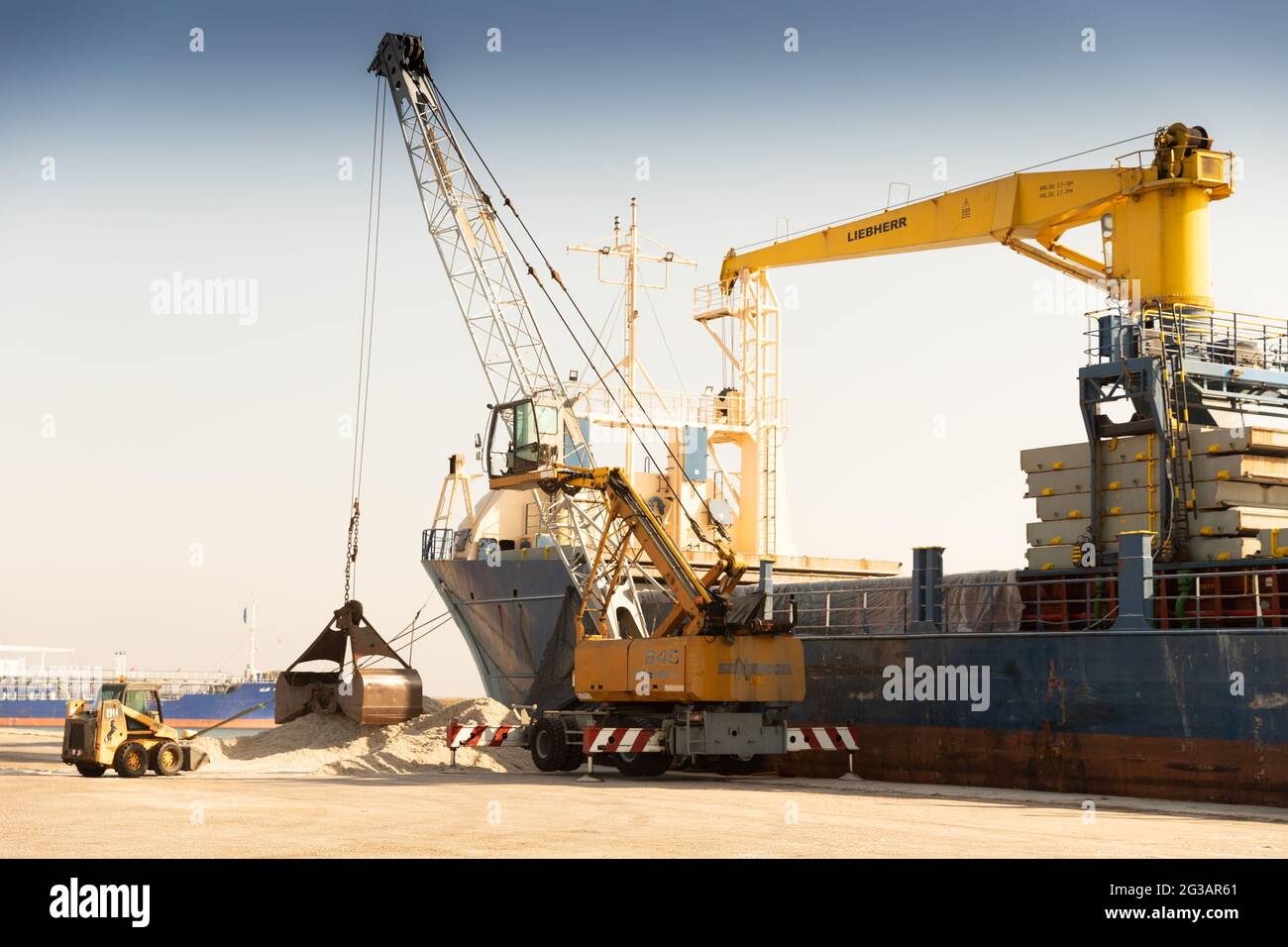 Crane with bucket loads cotton seed in a cargo ship to be exported from Greece Stock Photo