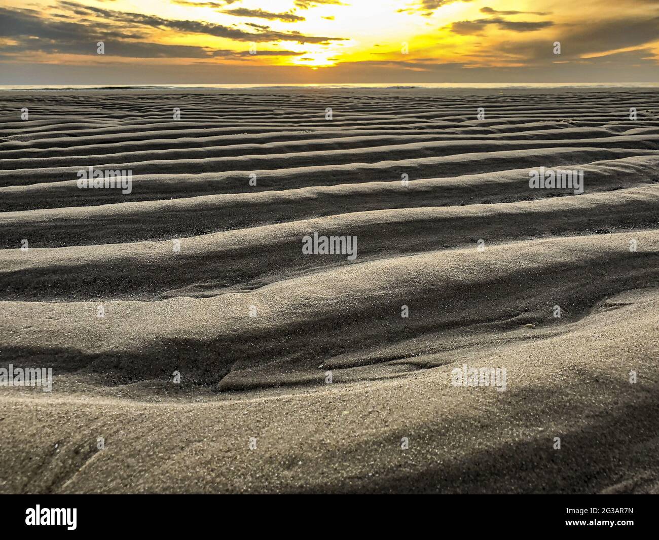 sandy beach with wave pattern at sunse Stock Photo
