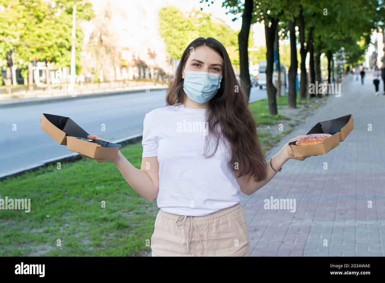A masked woman deliverer of food during a pandemic and quarantine keeps ...