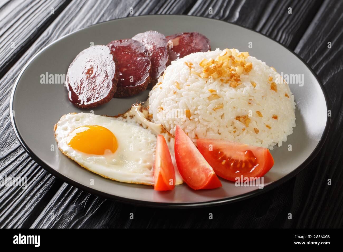 Filipino Fried Rice Recipe Sinangag with crispy garlic, egg and meat close up in the plate on the table. Horizontal Stock Photo