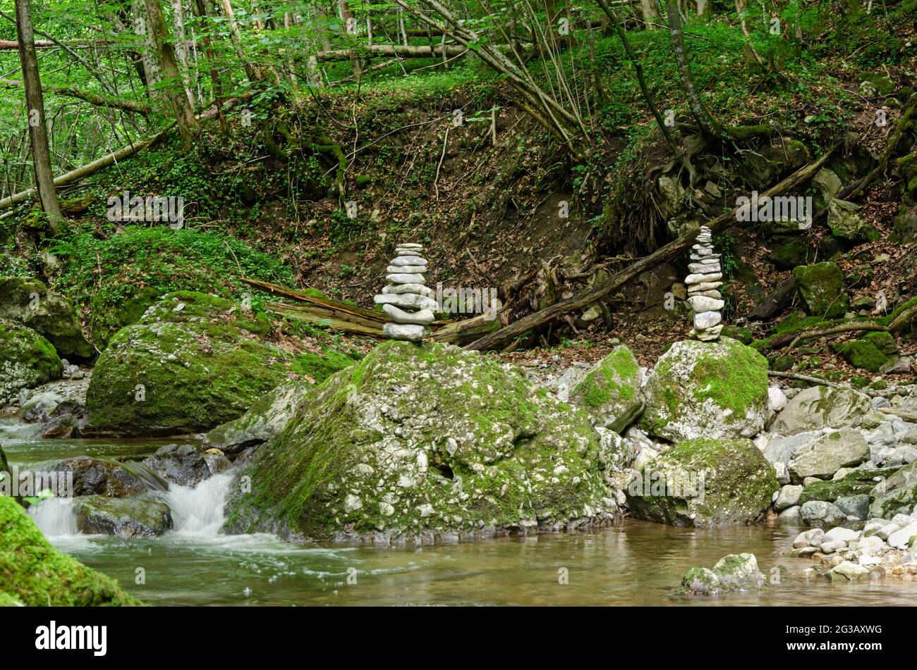 Two rock stacks in a streambed. Piles of stacked rocks, balancing on big rocks in a bed of a wild stream. Rocks laid flat upon each other. Stock Photo