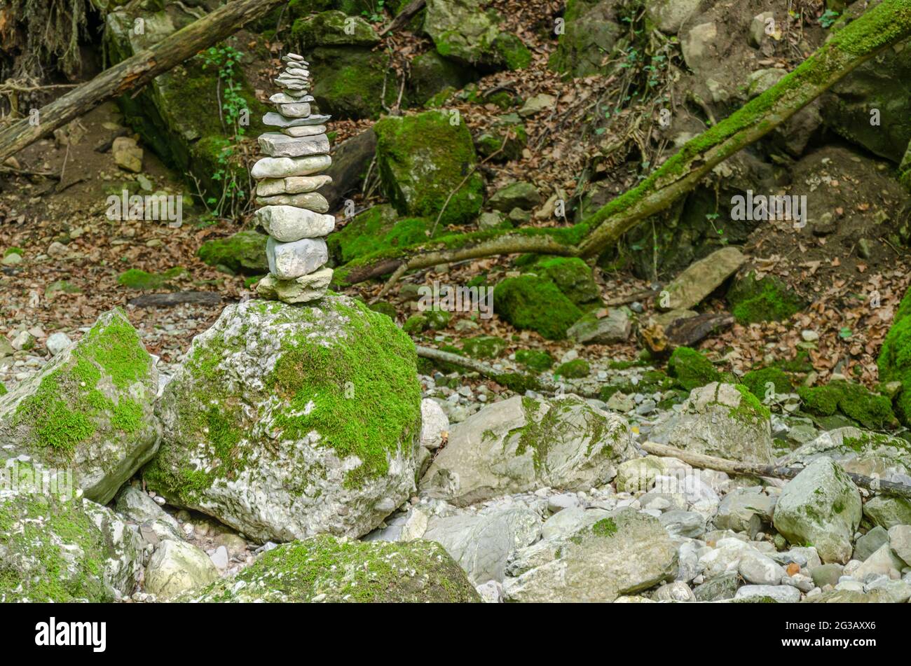 Single rock stack in a streambed. Pile of stacked rocks balancing on a big rock in a bed of a wild stream. Rocks laid flat upon each other. Stock Photo