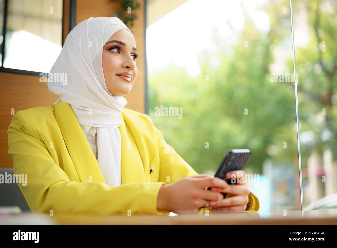 Young muslim woman in hijab using her smartphone in cafe Stock Photo ...