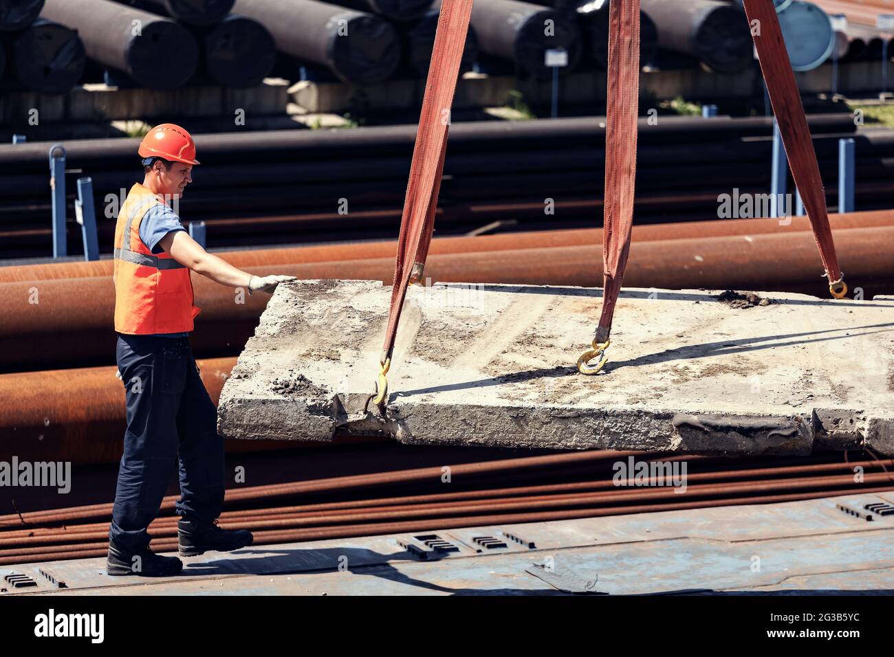 A slinger unloads concrete slabs on the street on a summer day. A
