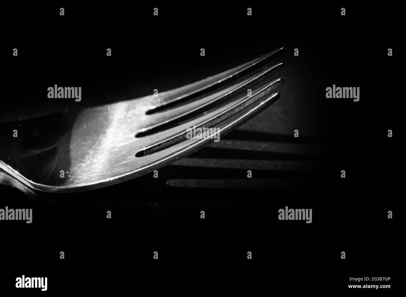 Black and white shot of a silver fork isolated on black Stock Photo