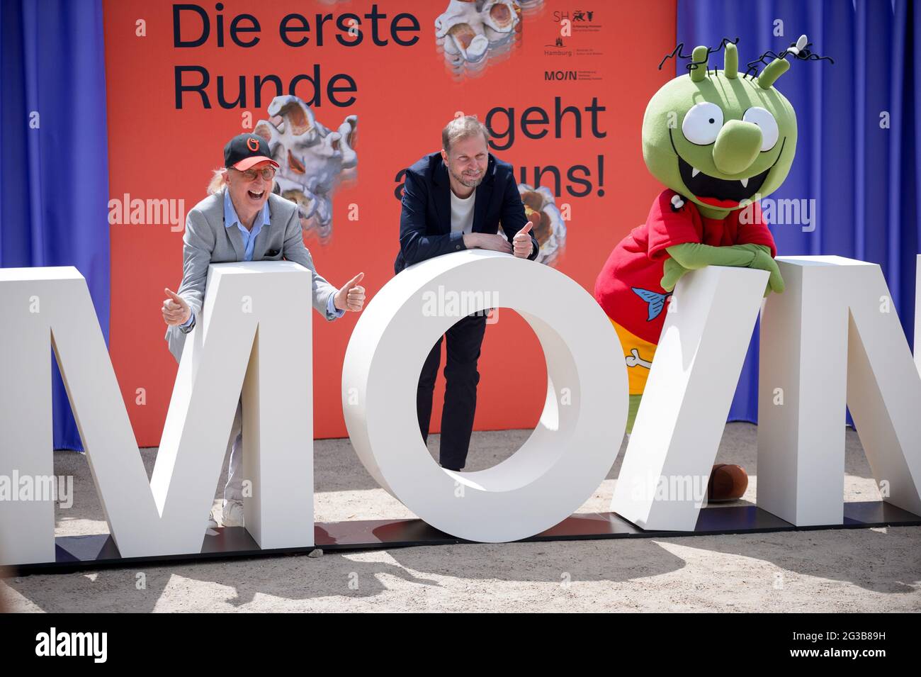 Hamburg, Germany. 15th June, 2021. Otto Waalkes (l-r), comedian, actor and director, gestures with Helge Albers, film producer and Managing Director of Moin Filmförderung Hamburg Schleswig-Holstein GmbH, and a character from the animated film 'Die Olchis' behind the lettering 'Moin' at a press event. On the occasion of the nationwide cinema release on 01 July 2021, MOIN Filmförderung Hamburg Schleswig-Holstein is luring viewers back into the halls with free cinema tickets. Credit: Jonas Walzberg/dpa/Alamy Live News Stock Photo