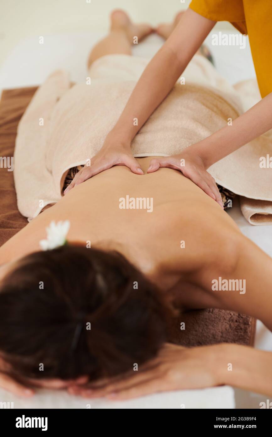 Young woman lying on sofa while getting medical massage from therapist Stock Photo