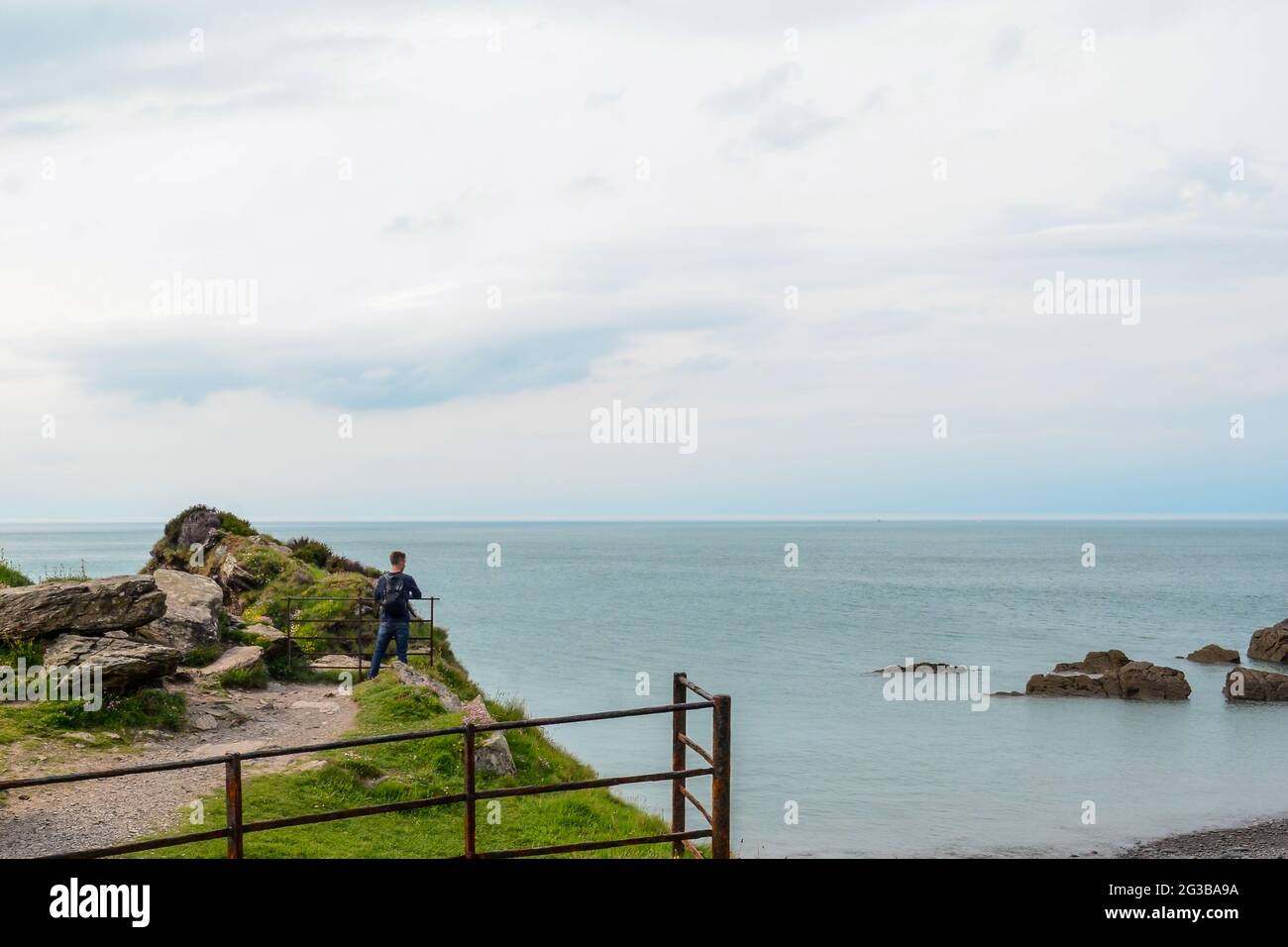 Man standing at the cliff edge looking at a view of the ocean Stock ...
