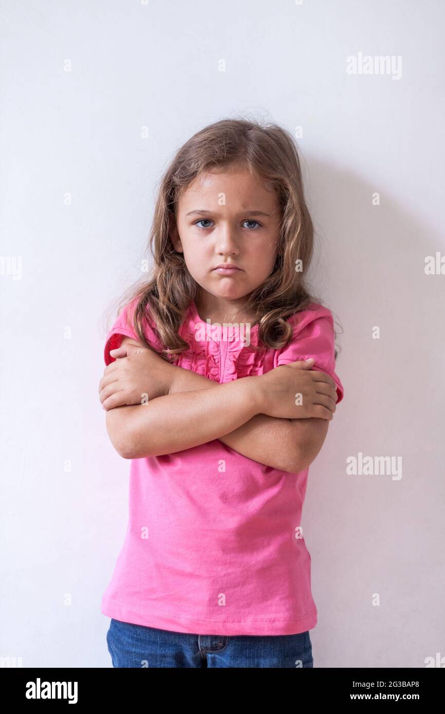 Portrait of Little Six-Year Sad Russian Girl With Expression Face In Pink T-Shirt On White Wall Background Close Up. Stock Photo