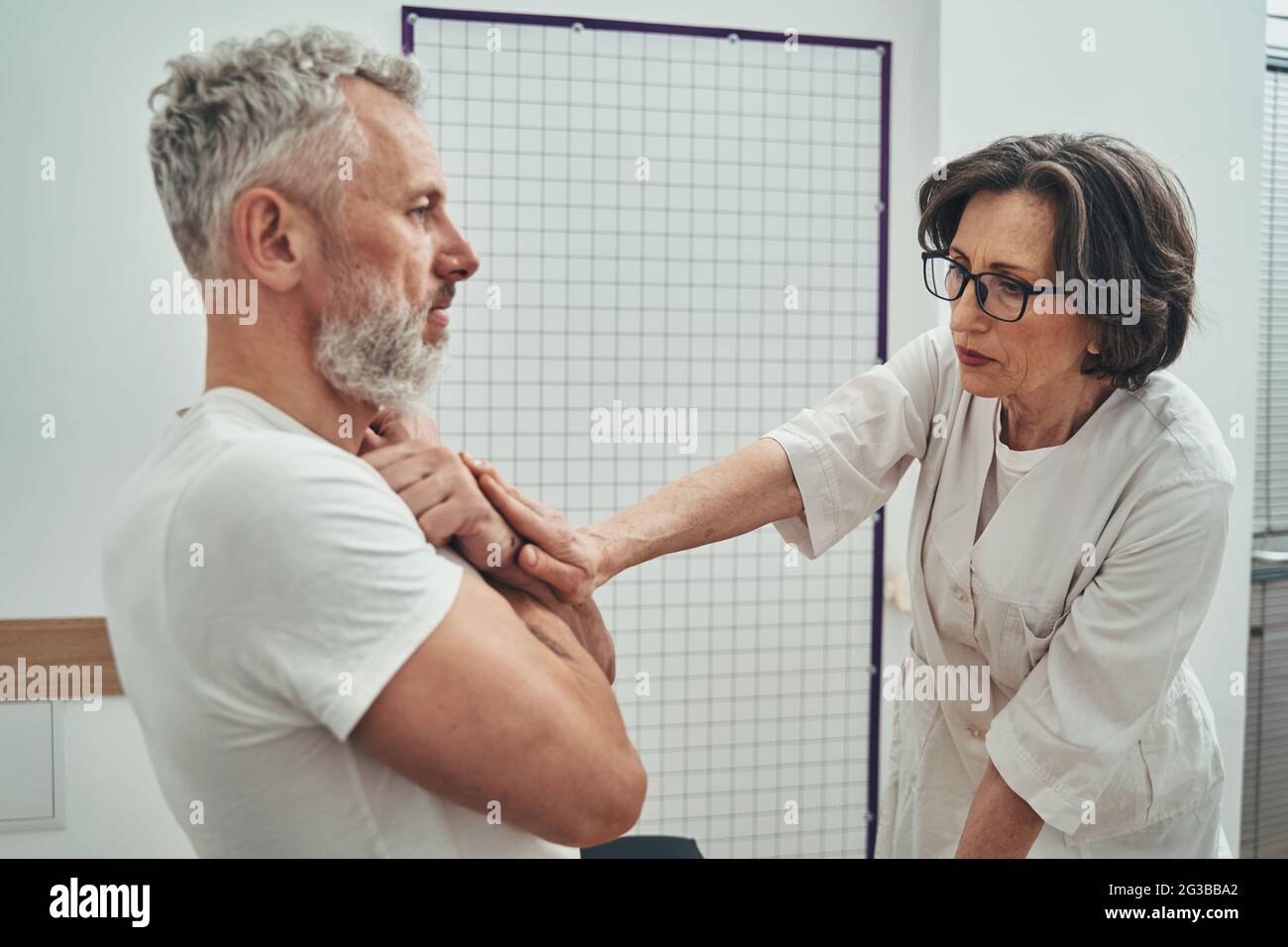 Lady doctor assessing the muscle strength of a mature man Stock Photo