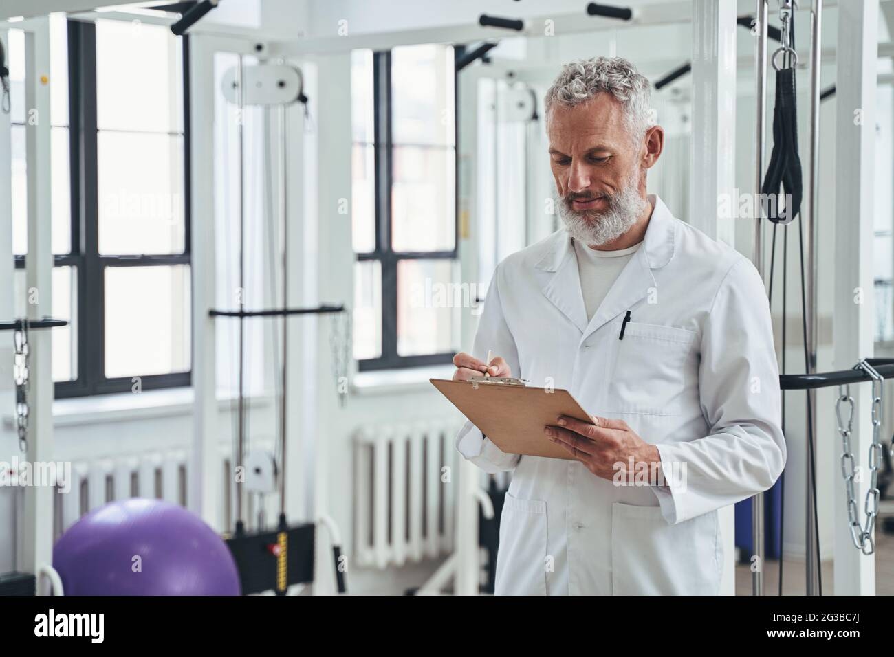 Professional kinesiologist taking notes during the physiotherapy session Stock Photo
