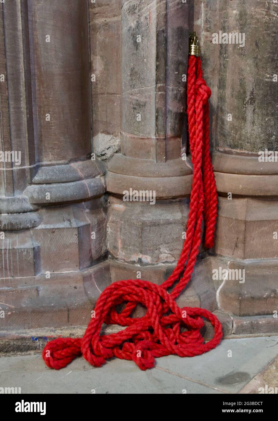 Red barrier rope with brass hook attached to wall in old building