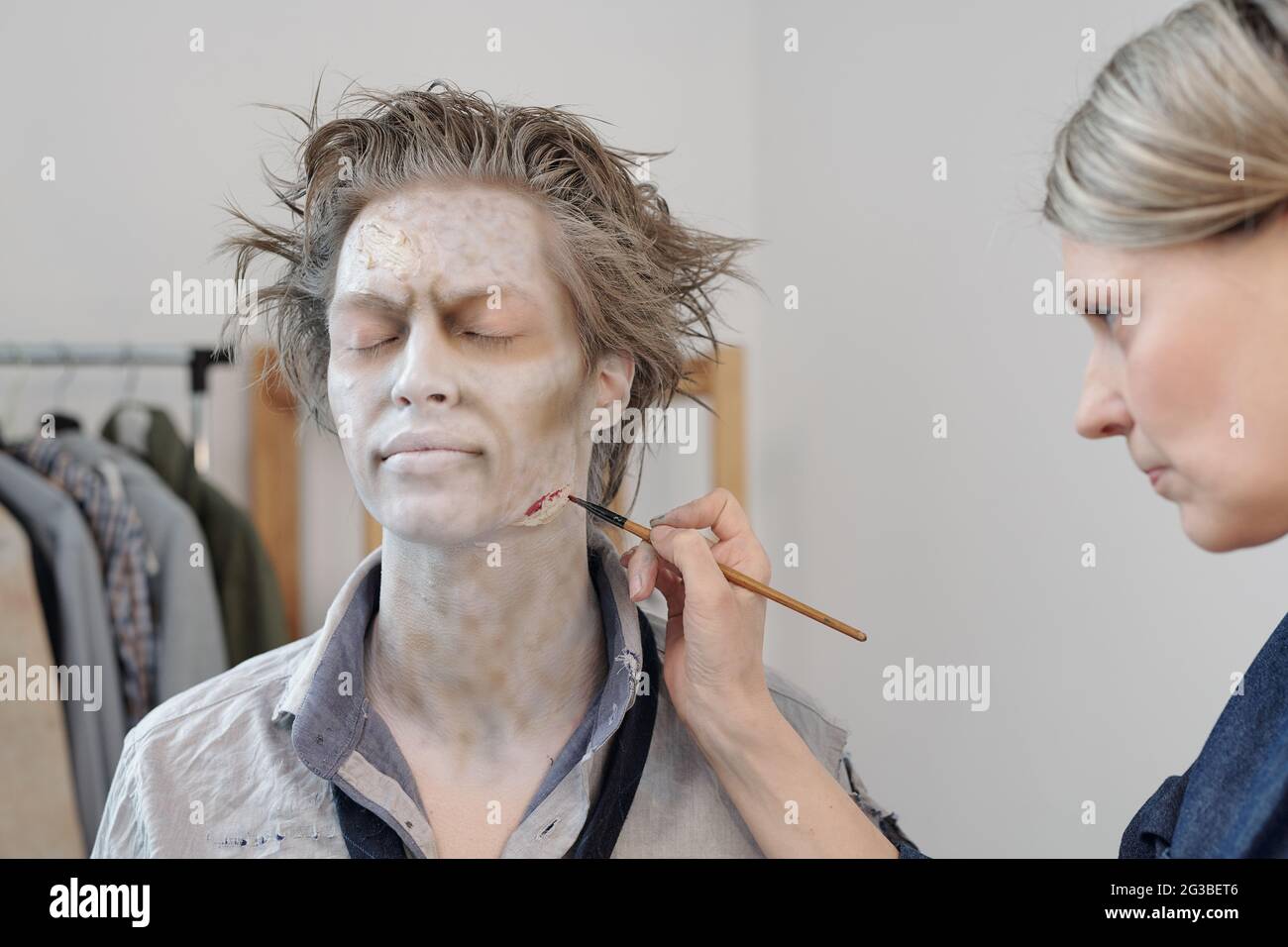 Stage makeup artist with paintbrush painting wound on face of young man  Stock Photo - Alamy