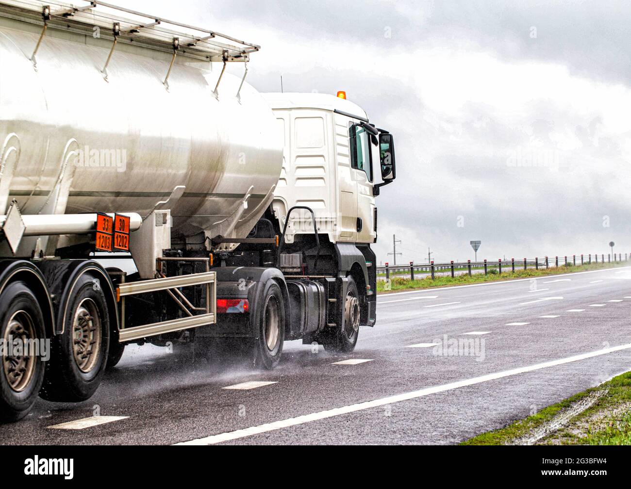 A white semitrailer tractor with a stainless tanker truck transports