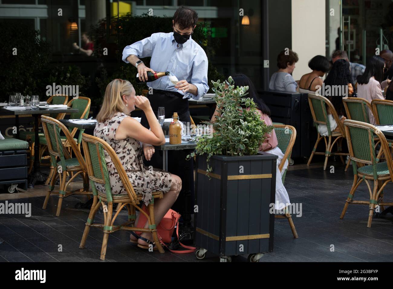 Customers enjoying a glass of champagne whilst sat outside at Côte restaurant along the Southbank in Central London, UK Stock Photo