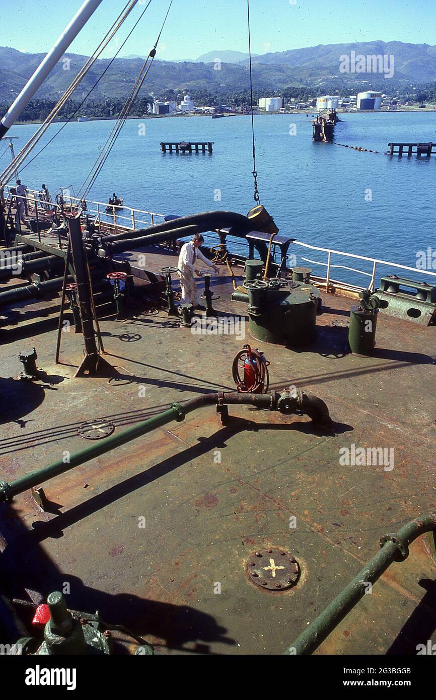 Oil Temrinal offloading operations shipside. Worker turns valve, Haiti Stock Photo