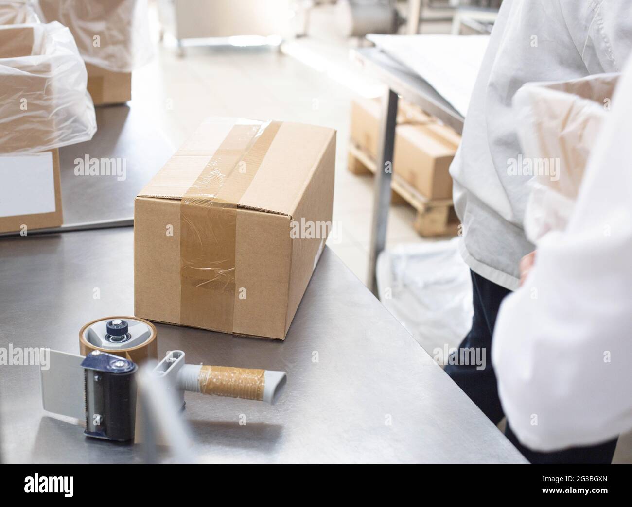 Worker packs cardboard boxes with finished goods at the factory. Stock Photo
