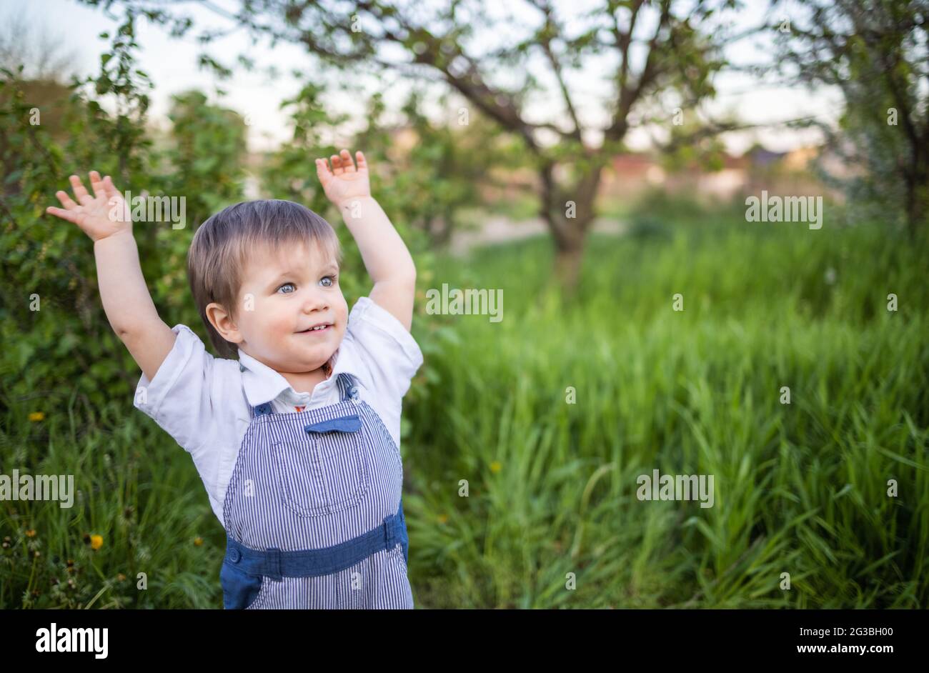 A little boy in denim overalls with expressive blue eyes. Jumping and