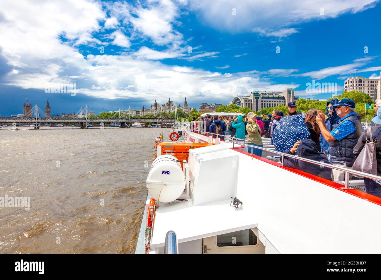 Tourists enjoying a Thames river cruise tour on a boat with Big Ben and Houses of Parliament up front, London, UK Stock Photo