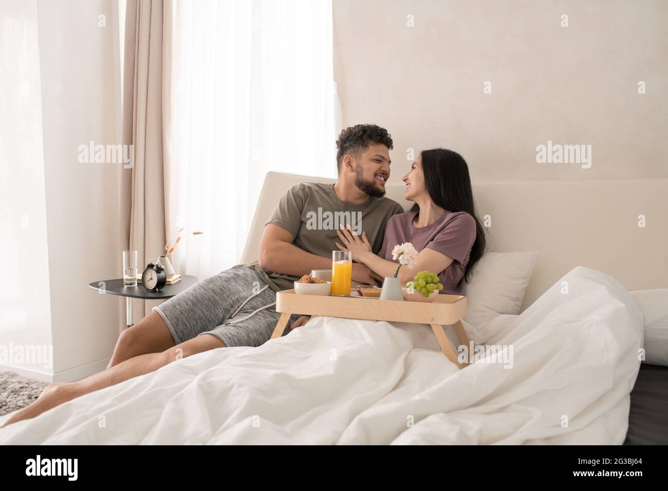 Happy young couple enjoying breakfast in bed during travel Stock Photo