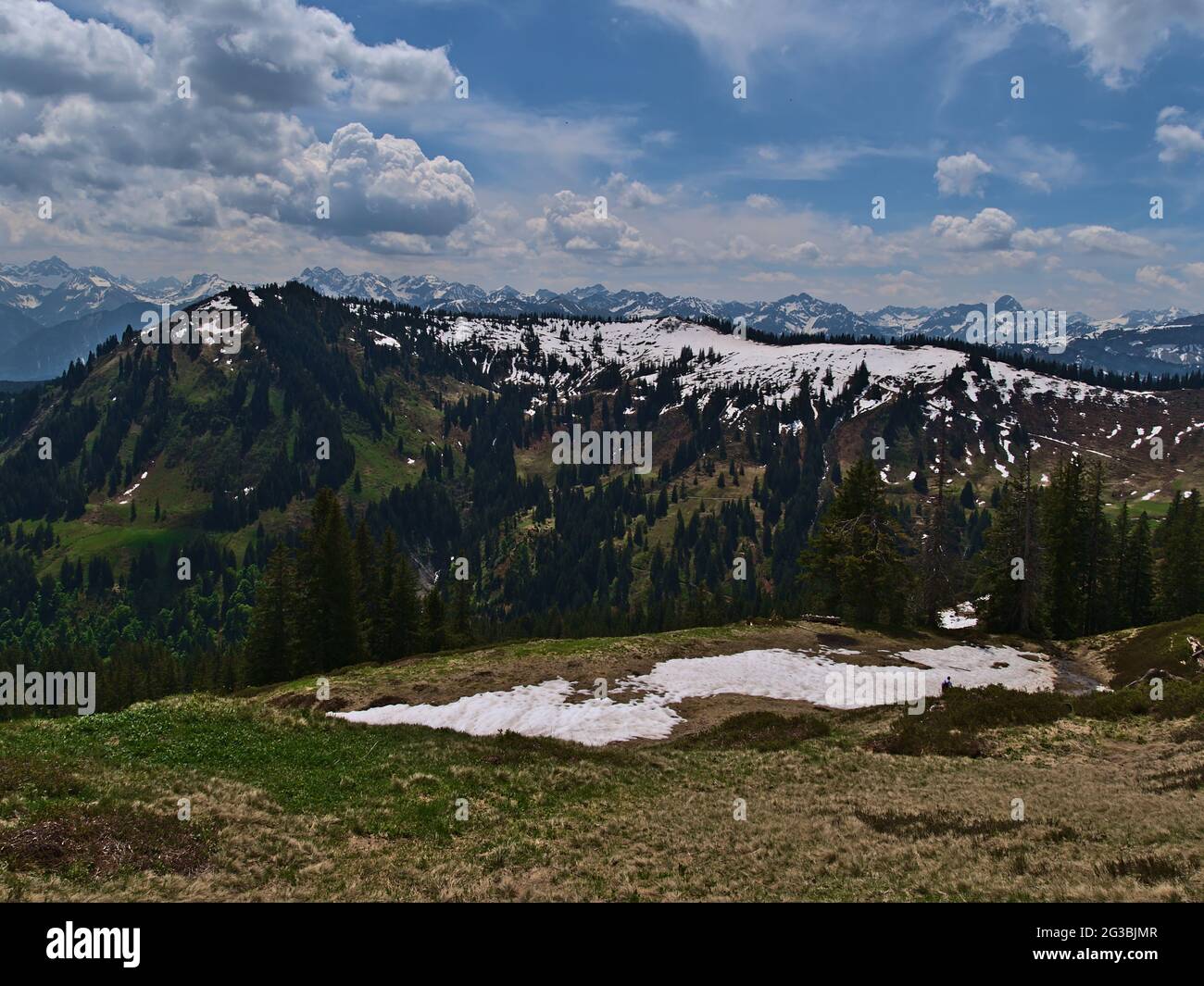 Mountain landscape in the Allgäu Alps in southern Bavaria, Germany on sunny day in early summer with residual snow, meadows, trees and mountains. Stock Photo