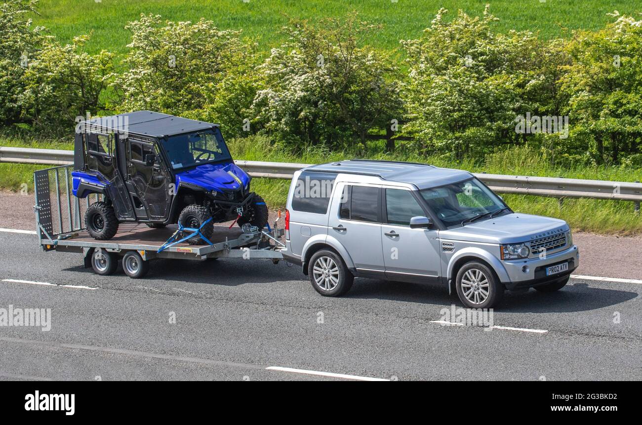Blue ATV being towed by 2012 Land Rover Discovery Xs Sdv6 Auto, travelling on the M61 Motorway UK Stock Photo