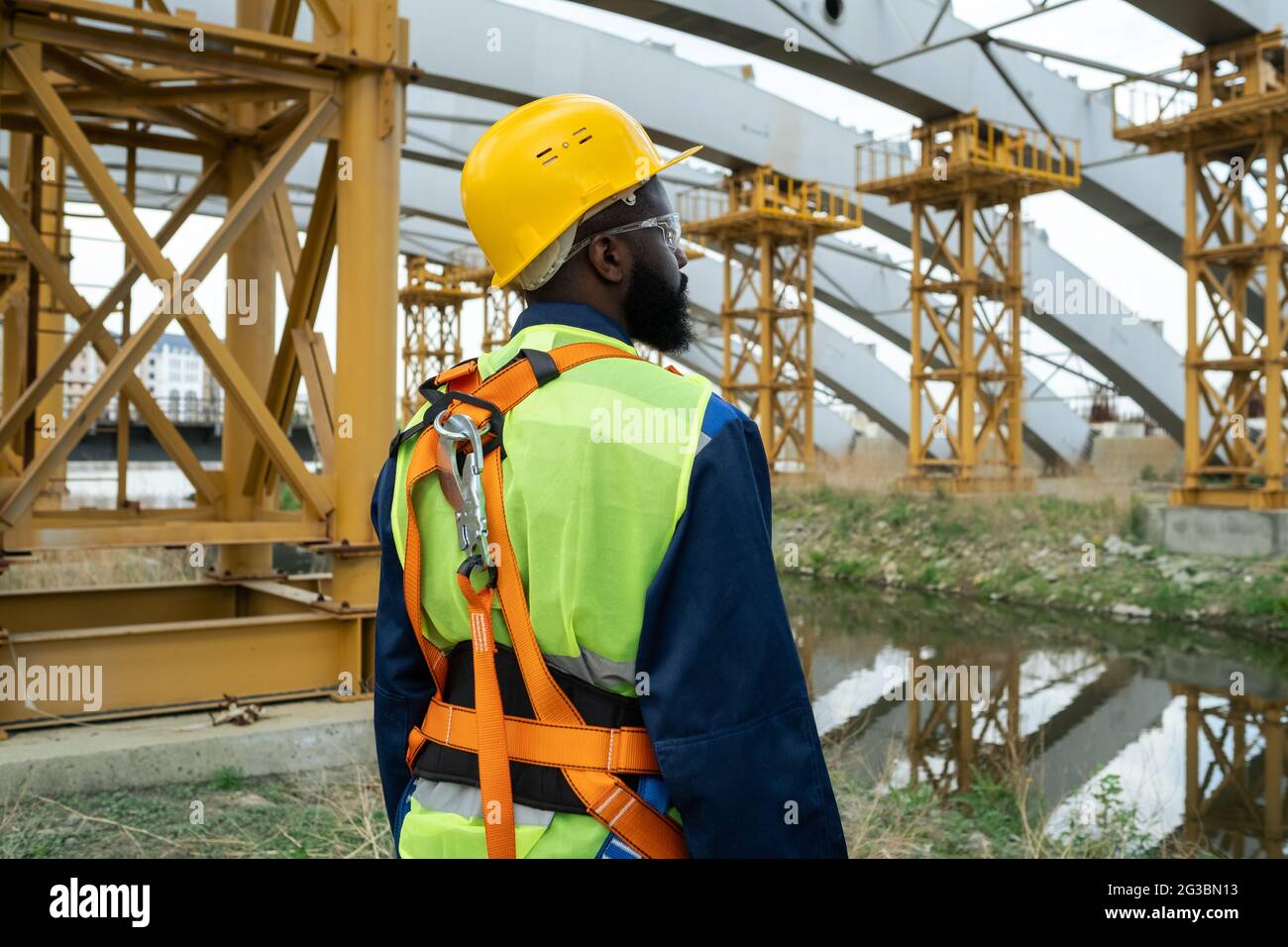 Young African engineer standing on construction site and looking at huge frames Stock Photo