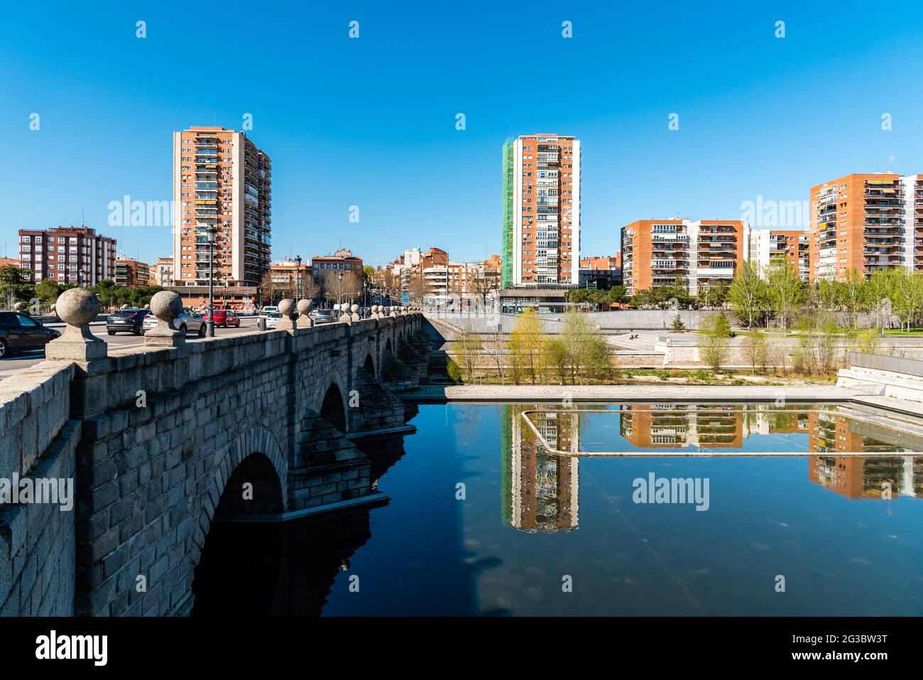 Madrid, Spain - March 14, 2021: Madrid Rio. Bridge of Segovia and Puerta del Angel quarter. Reflections of residential towers on water Stock Photo
