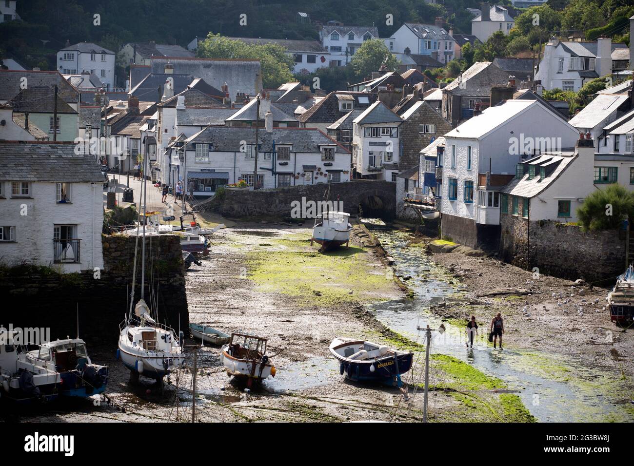 With the tide out a couple stroll among the boats in the small picturesque fishing village and harbour town of Polperro in south Cornwall. As the Coro Stock Photo