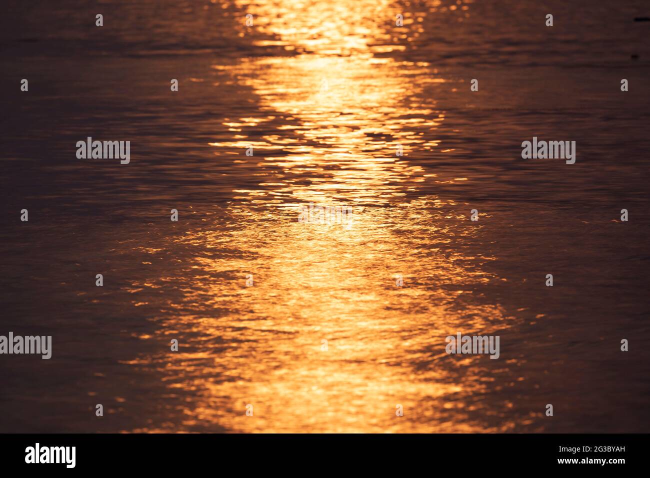 Orange and a bit purple sunset sunlight, reflected on the uneven surface of the water, on the island of Koh Chang, Gulf of Thailand Stock Photo