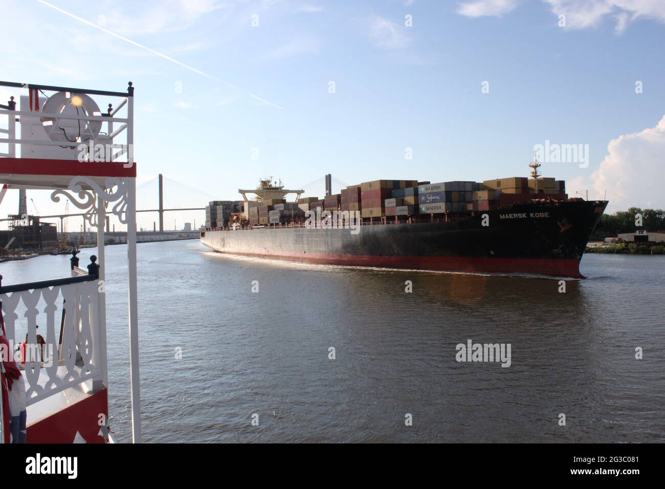 Massive Container ship passing a tourist Paddle steamer on the Savannah river Georgia USA in the late afternoon. Stock Photo