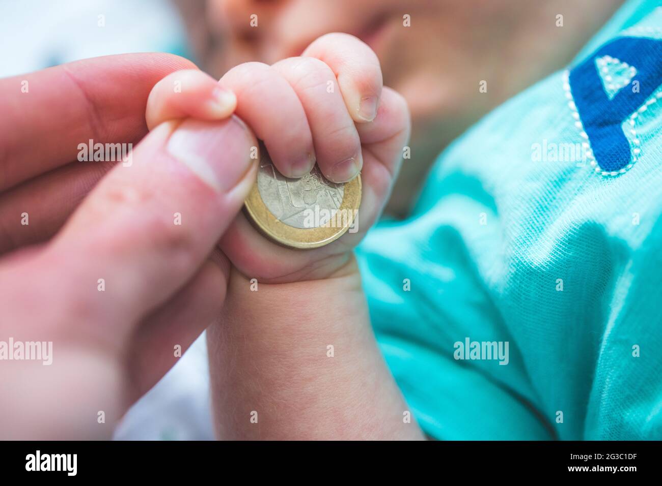 Close up of newborn baby hands holding a coin, retirement arrangement concept Stock Photo