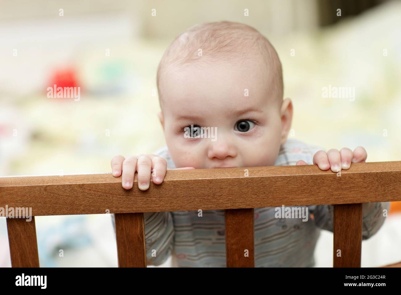The baby boy biting a wooden cot at home Stock Photo Alamy