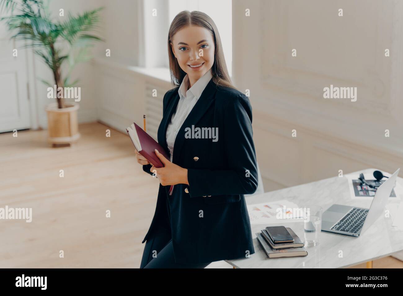 Professional business woman smiling at camera with notebook in hands Stock Photo