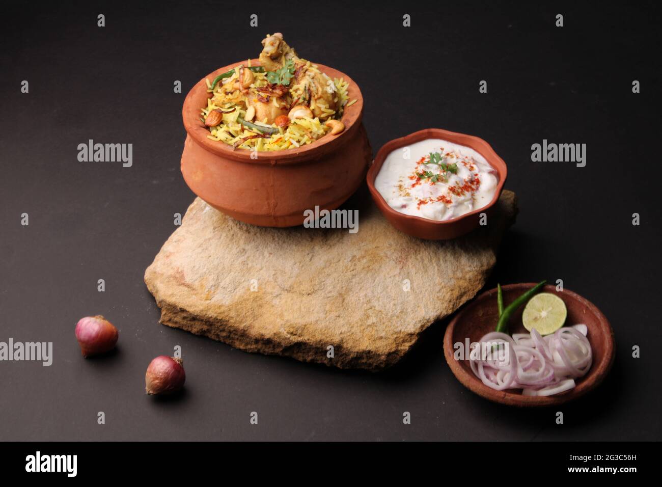Dum Raita Spicy chicken dum biryani in traditional handi or clay pot. served with ...