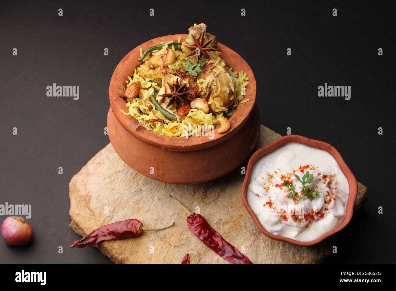 Dum Raita Spicy chicken dum biryani in traditional handi or clay pot. served with ...