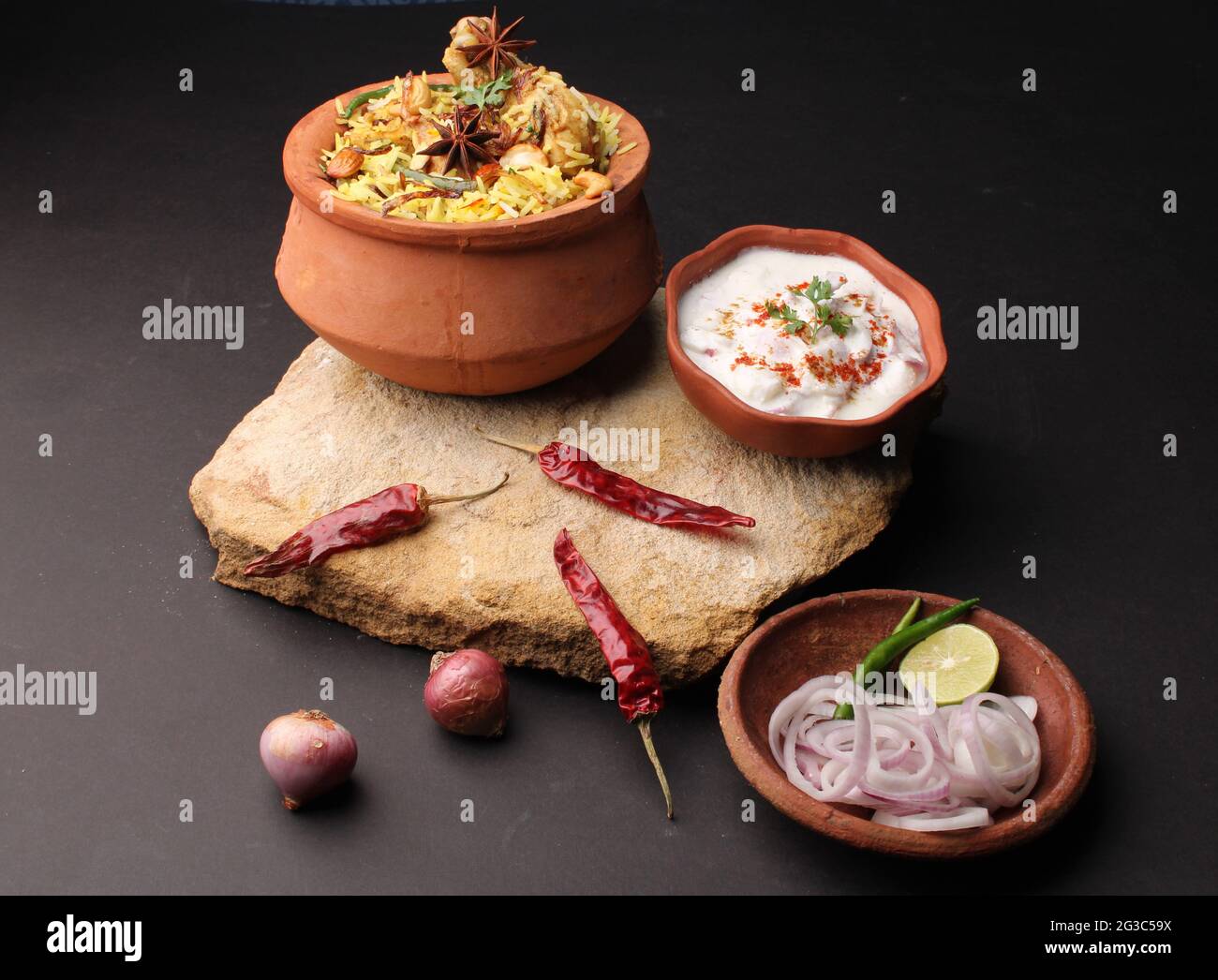 Dum Raita Spicy chicken dum biryani in traditional handi or clay pot. served with ...