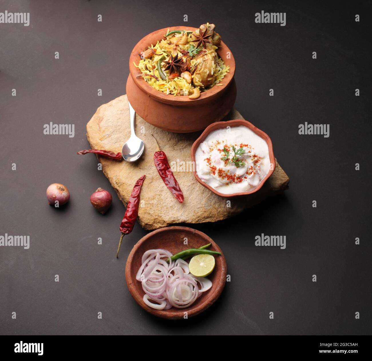 Dum Raita Spicy chicken dum biryani in traditional handi or clay pot. served with ...