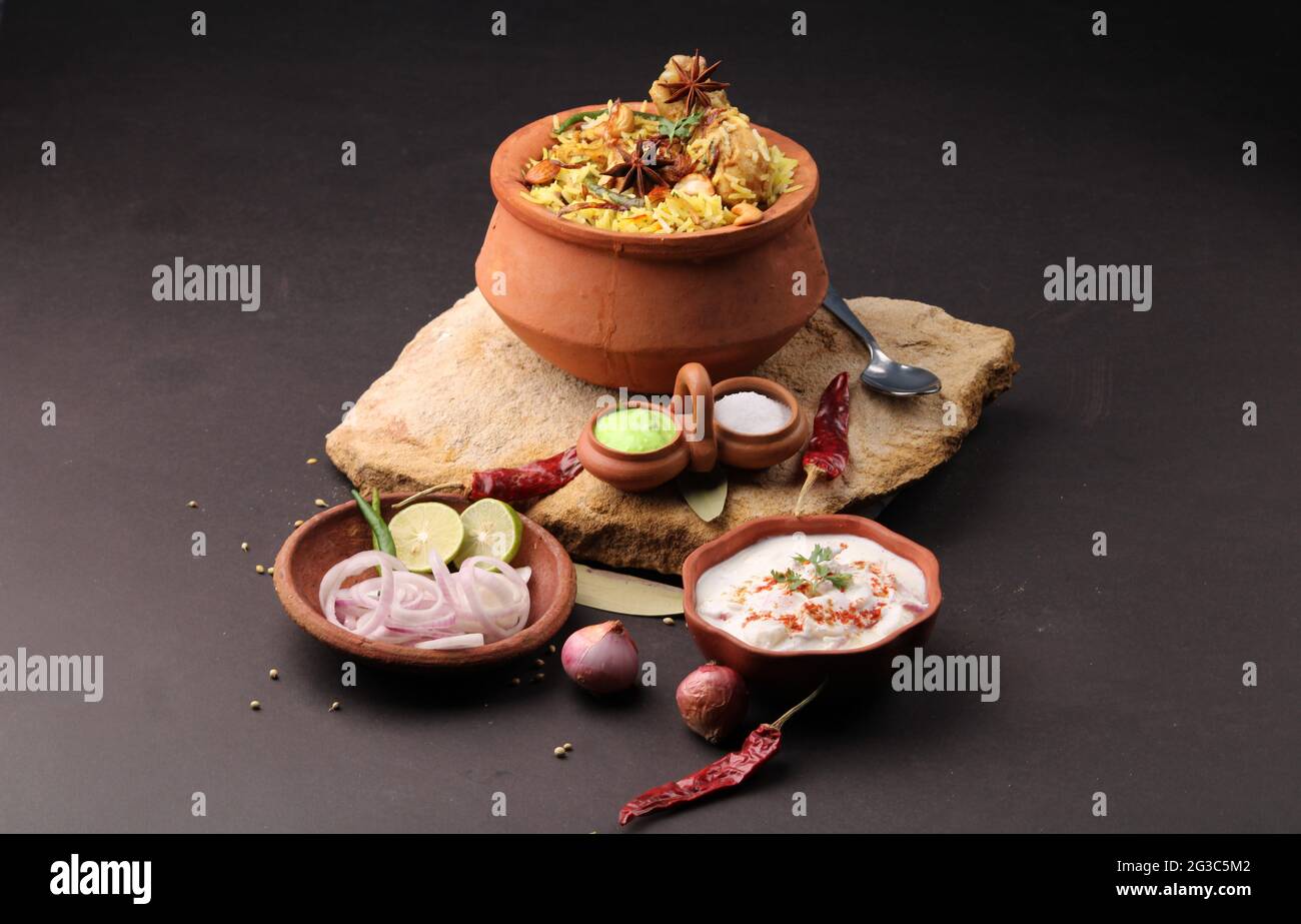 Dum Raita Spicy chicken dum biryani in traditional handi or clay pot. served with ...