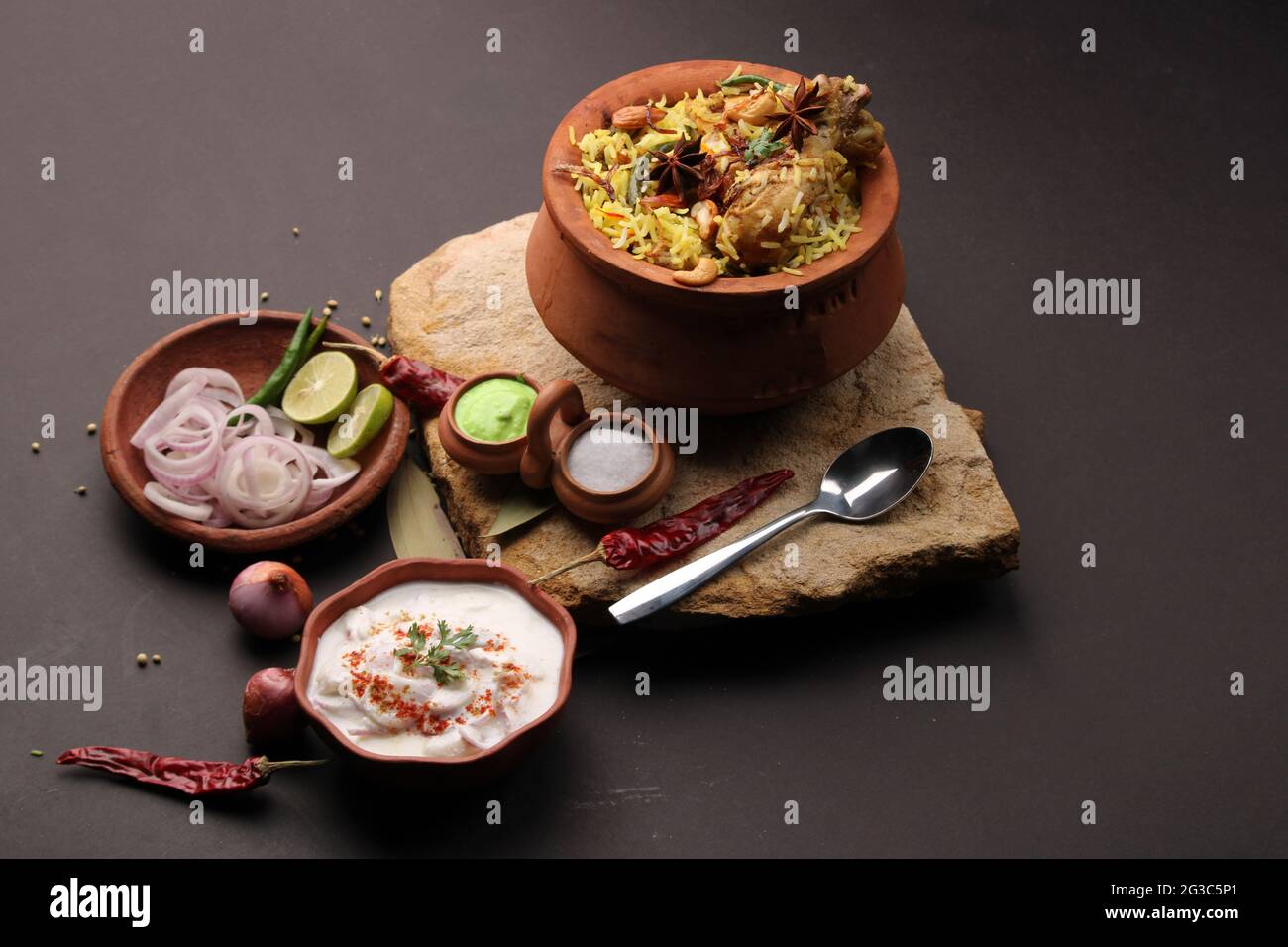 Dum Raita Spicy chicken dum biryani in traditional handi or clay pot. served with ...