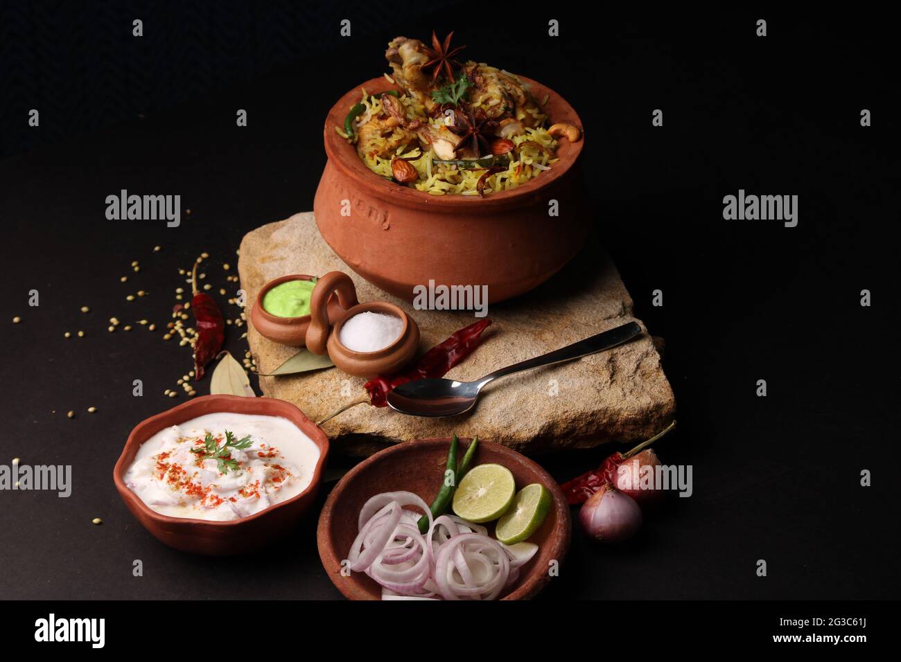 Dum Raita Spicy chicken dum biryani in traditional handi or clay pot. served with ...