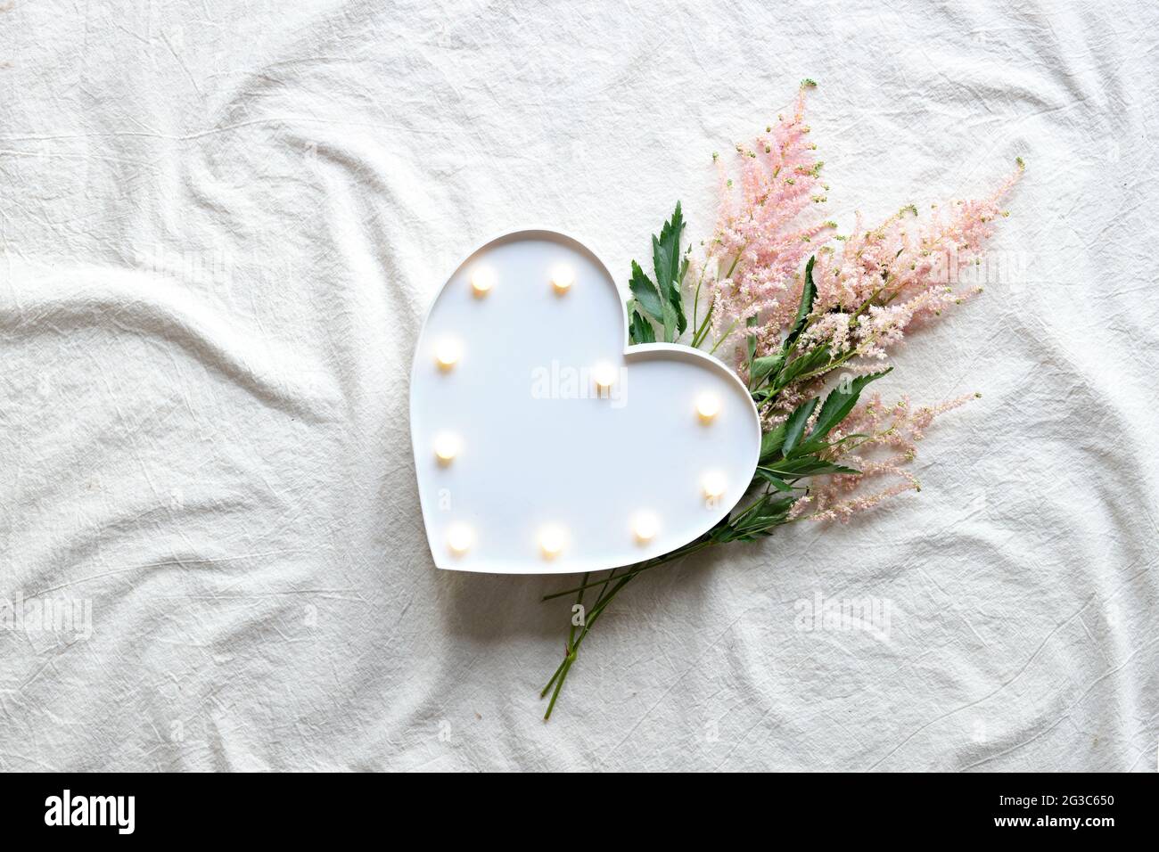 Heart lightbox and wild flowers . Flat lay on off white textile. Natural materials, environment concious, low impact, eco friendly lifestyle concept. Stock Photo