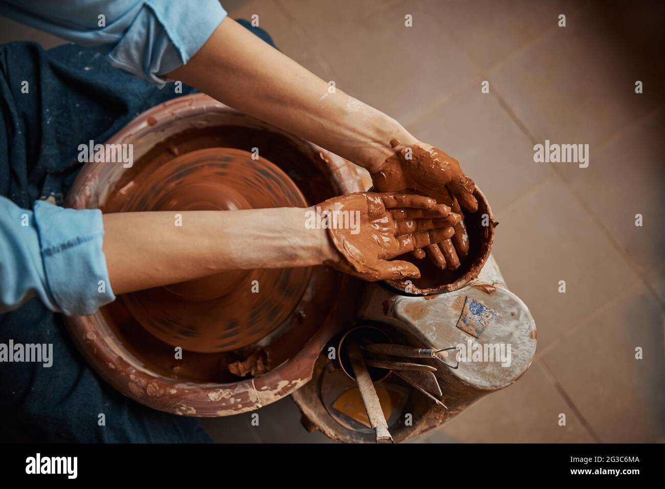 Craft woman working in pottery workshop while making ceramic tableware Stock Photo