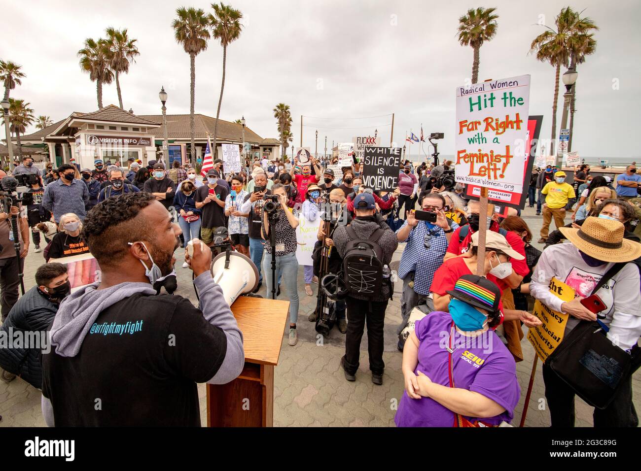 Masked against the coronavirus, an African American speaker addresses a Black Lives Matter demonstration in Huntington Beach, CA. Note variety of issu Stock Photo