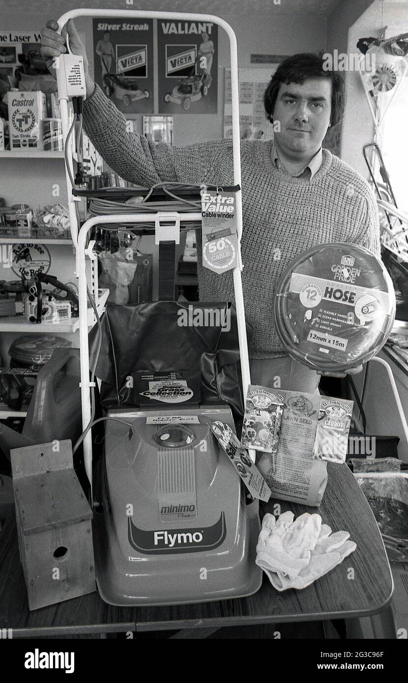 1980s, a shopkeeper showing the latest in electric hover lawnmowers, a 'Flymo', minimo Plus, England, UK.  Invented in 1964 by Swede Karl Dahiman, after being inspired by Christopher Cockerell's Hovercraft, the design of the lightweight 'flying' rotary mower, where it floated about the grass, meant it was more manoeuvrable and far easier to push than a conventional and often heavy, wheeled petrol mower. Launched to the public in 1965, the light and agile Flymo introduced its first electric model in 1969 and went on to become a leading product in the world of lawn care and remains so today, Stock Photo