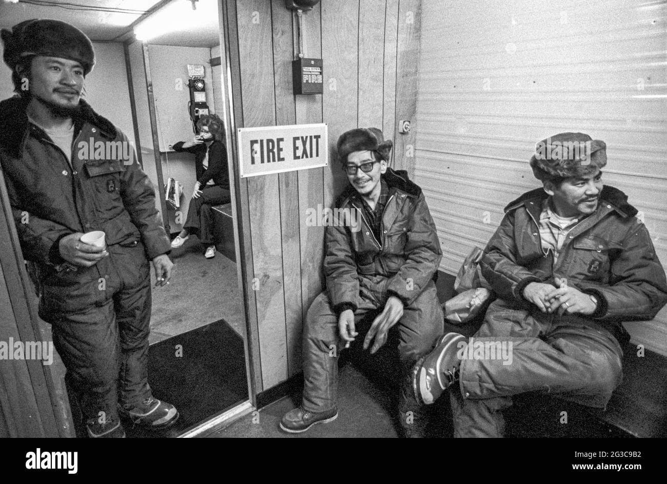 Wearing winter coats and fur hats, oil field workers in Prudhoe Bay, Alaska, relax indoors after an outdoor working shift. Stock Photo