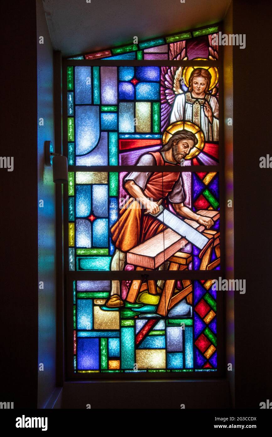 Depicted in a Catholic church stained glass window as a carpenter, Saint Joseph is a figure in the canonical gospels who was married to Mary, mother o Stock Photo